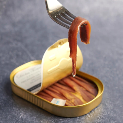 Filete de anchoa de costera servido con tenedor junto a la lata